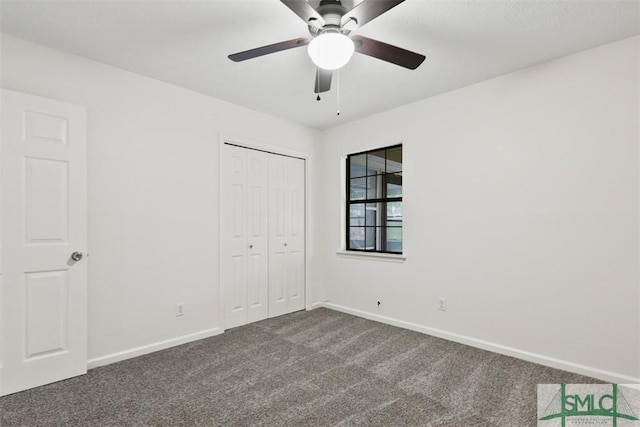 unfurnished bedroom with ceiling fan, dark carpet, and a closet