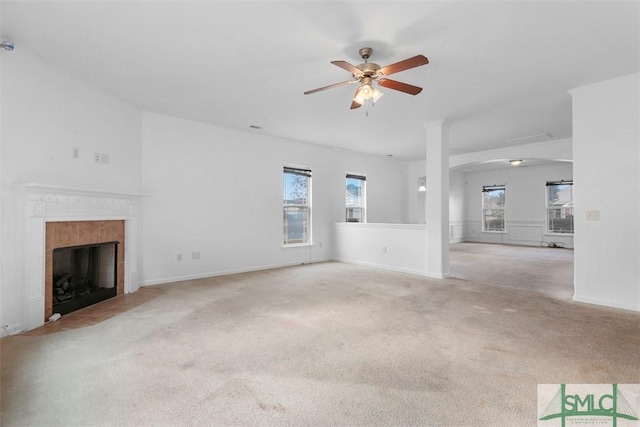 unfurnished living room with ceiling fan, a healthy amount of sunlight, light colored carpet, and a tile fireplace