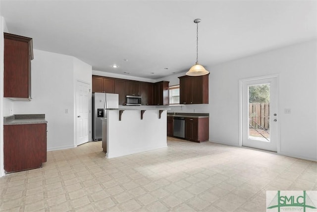 kitchen with a center island, stainless steel appliances, hanging light fixtures, and a breakfast bar area