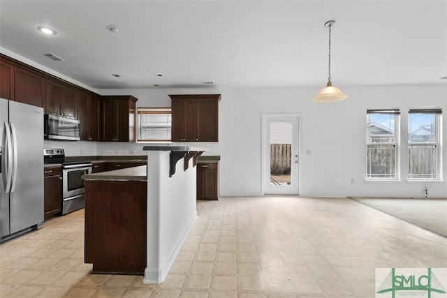 kitchen with a kitchen breakfast bar, a wealth of natural light, a kitchen island, and appliances with stainless steel finishes