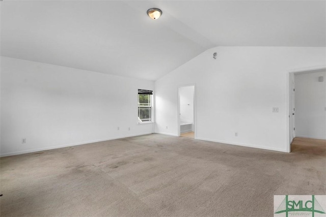 carpeted spare room featuring vaulted ceiling