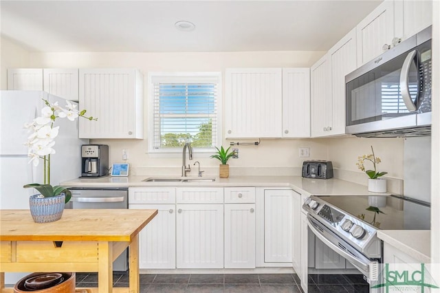 kitchen with white cabinetry, sink, dark tile patterned floors, and appliances with stainless steel finishes