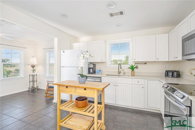 kitchen with dark tile patterned floors, white cabinetry, sink, and stainless steel appliances