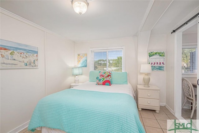 bedroom featuring a barn door, crown molding, and light tile patterned floors