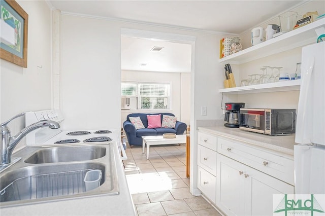 kitchen with crown molding, sink, light tile patterned floors, white cabinets, and white fridge