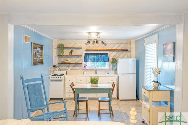 kitchen featuring white appliances, a wealth of natural light, ornamental molding, and light tile patterned flooring