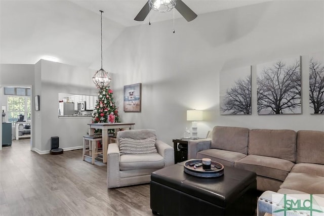 living room featuring wood-type flooring, ceiling fan with notable chandelier, and high vaulted ceiling