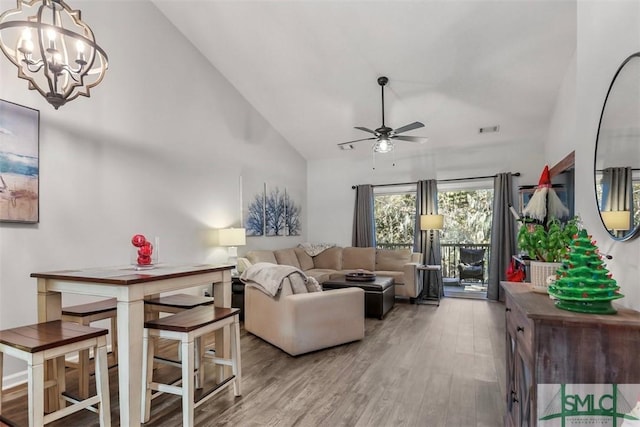 living room featuring ceiling fan with notable chandelier, hardwood / wood-style flooring, and high vaulted ceiling