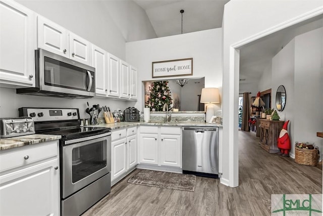 kitchen featuring light stone counters, stainless steel appliances, high vaulted ceiling, hardwood / wood-style floors, and white cabinetry