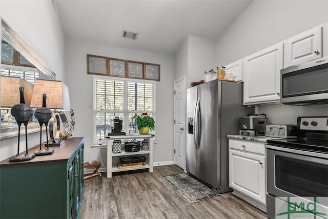 kitchen with a wealth of natural light, white cabinets, and appliances with stainless steel finishes