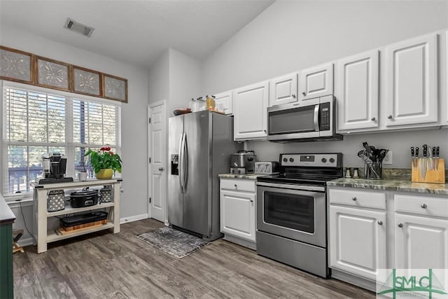 kitchen featuring white cabinets, stainless steel appliances, vaulted ceiling, and dark wood-type flooring