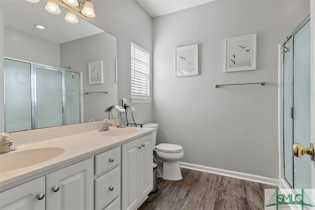 bathroom with hardwood / wood-style flooring, vanity, toilet, and a shower with door