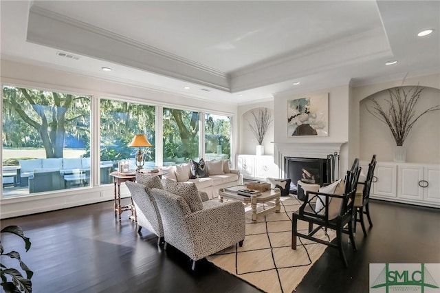 living room with hardwood / wood-style floors, a raised ceiling, and crown molding