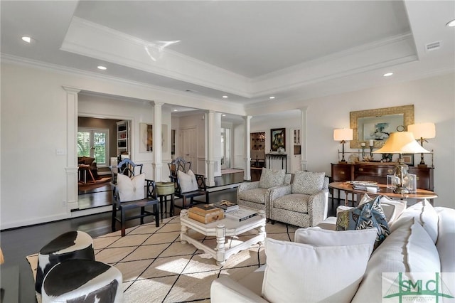 living room with ornamental molding, light hardwood / wood-style flooring, a tray ceiling, and decorative columns