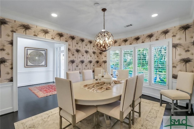 dining space featuring hardwood / wood-style floors, crown molding, and a notable chandelier