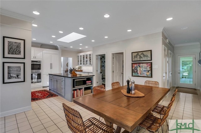 tiled dining space with crown molding and a skylight