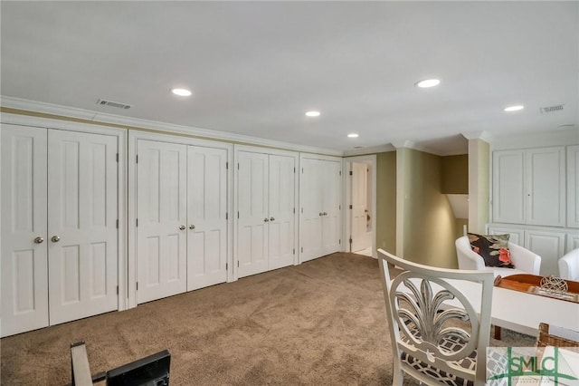 carpeted bedroom featuring ornamental molding and two closets