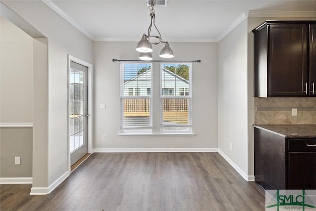 unfurnished dining area featuring hardwood / wood-style floors, a notable chandelier, and ornamental molding