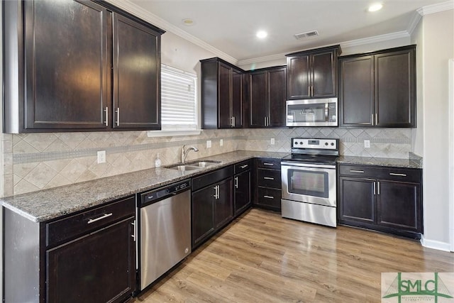 kitchen featuring sink, dark stone countertops, light wood-type flooring, appliances with stainless steel finishes, and dark brown cabinetry