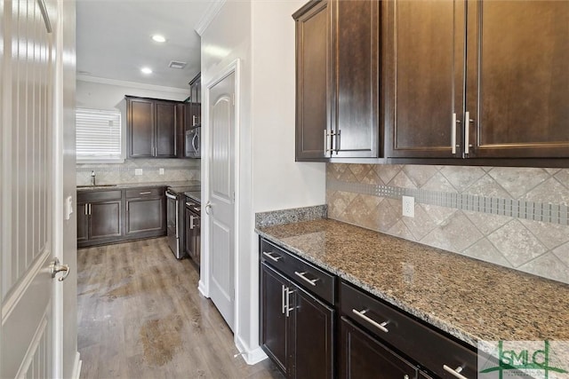 kitchen featuring ornamental molding, stainless steel appliances, light stone counters, and light hardwood / wood-style floors