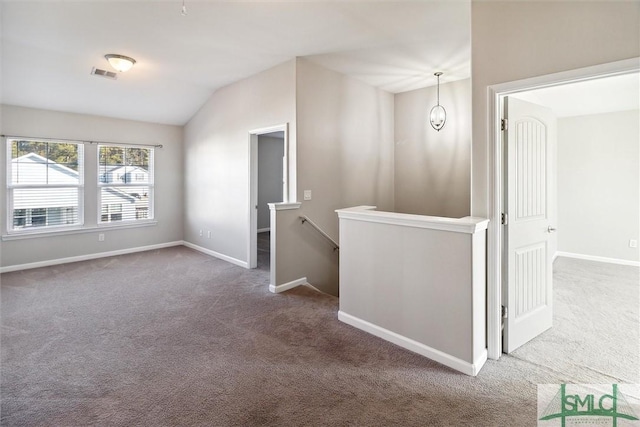 carpeted empty room with vaulted ceiling