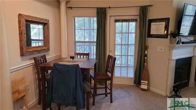 carpeted dining space featuring decorative columns and a fireplace