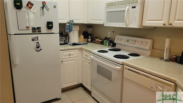 kitchen with light tile patterned flooring, white appliances, and white cabinetry