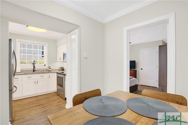 dining space with crown molding, light hardwood / wood-style flooring, and sink