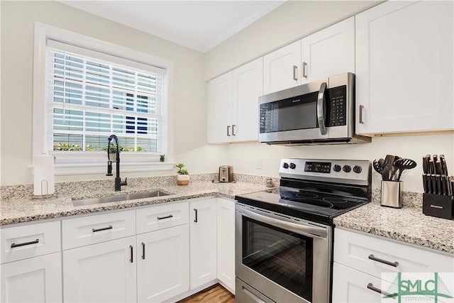 kitchen featuring light stone counters, stainless steel appliances, crown molding, sink, and white cabinets