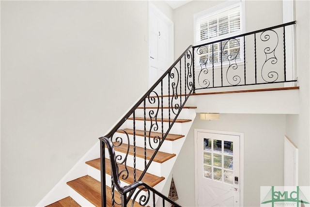 stairs with a healthy amount of sunlight and hardwood / wood-style flooring