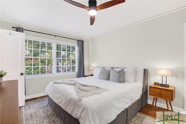 bedroom with ceiling fan, crown molding, and dark wood-type flooring