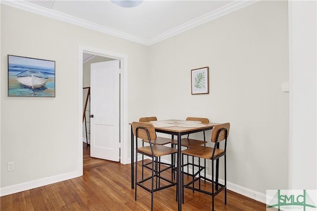 dining area with ornamental molding and dark wood-type flooring