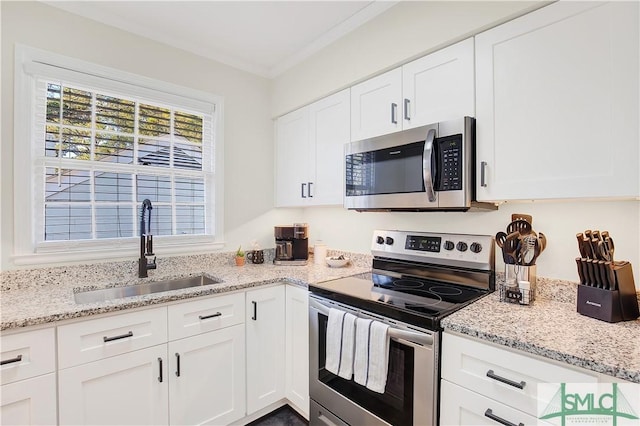 kitchen featuring white cabinetry, sink, light stone countertops, stainless steel appliances, and crown molding