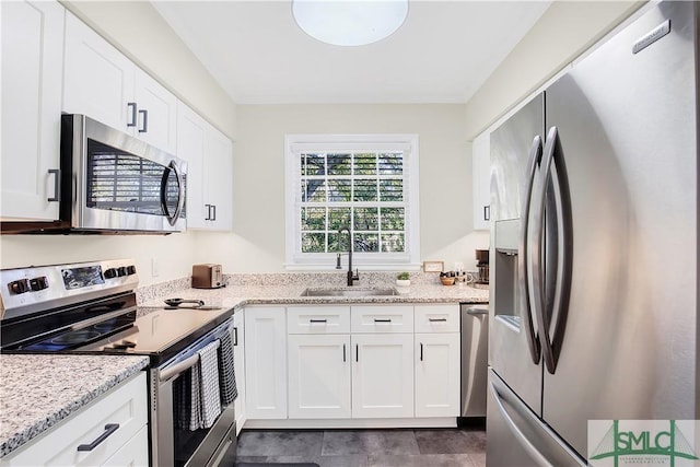 kitchen with light stone counters, sink, white cabinetry, and stainless steel appliances