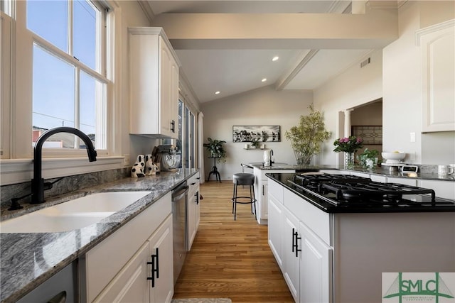 kitchen featuring white cabinetry, black gas stovetop, lofted ceiling, and sink