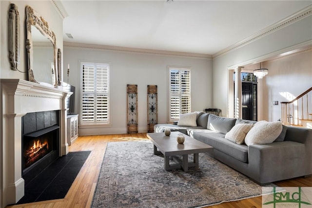 living room featuring a fireplace, light wood-type flooring, and ornamental molding