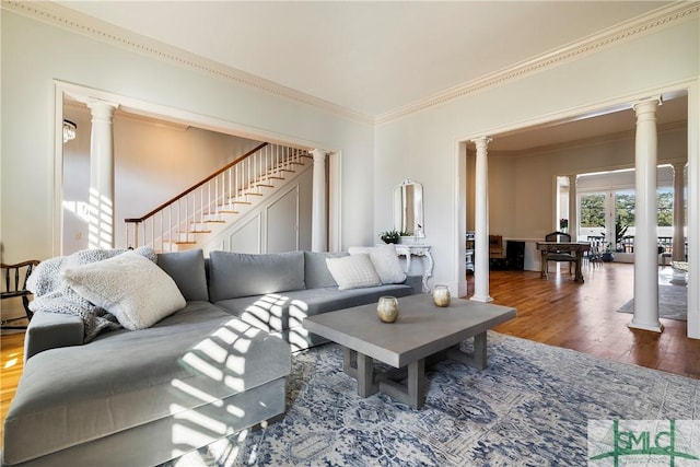 living room featuring ornate columns, wood-type flooring, and ornamental molding