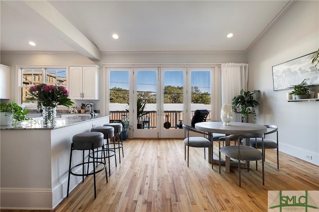 dining space with light hardwood / wood-style floors, ornamental molding, and sink