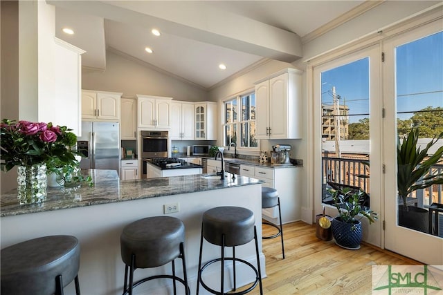 kitchen featuring kitchen peninsula, white cabinets, stainless steel appliances, and vaulted ceiling