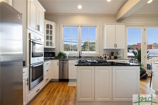 kitchen featuring beam ceiling, light hardwood / wood-style flooring, white cabinets, and appliances with stainless steel finishes