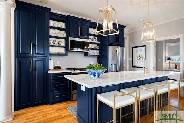 kitchen featuring blue cabinets, an island with sink, pendant lighting, appliances with stainless steel finishes, and light wood-type flooring