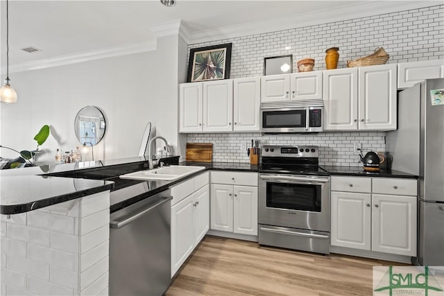 kitchen featuring kitchen peninsula, appliances with stainless steel finishes, tasteful backsplash, pendant lighting, and white cabinets