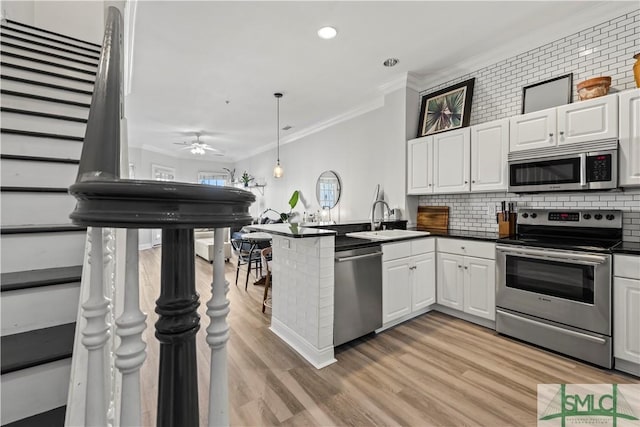 kitchen with kitchen peninsula, stainless steel appliances, white cabinetry, and sink