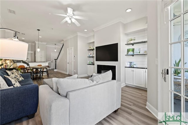 living room with ceiling fan, a healthy amount of sunlight, built in features, and light hardwood / wood-style flooring