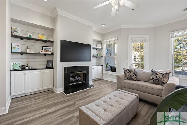 living room with ceiling fan, crown molding, and light hardwood / wood-style flooring