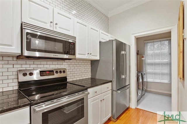 kitchen featuring white cabinets, washer and clothes dryer, crown molding, and stainless steel appliances