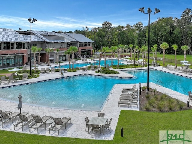 community pool featuring a patio area, stairway, and a yard