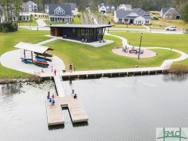 view of home's community featuring a dock, a water view, a lawn, and a residential view