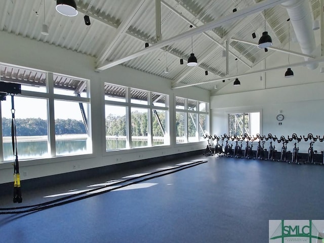 exercise room featuring ceiling fan, high vaulted ceiling, and a water view