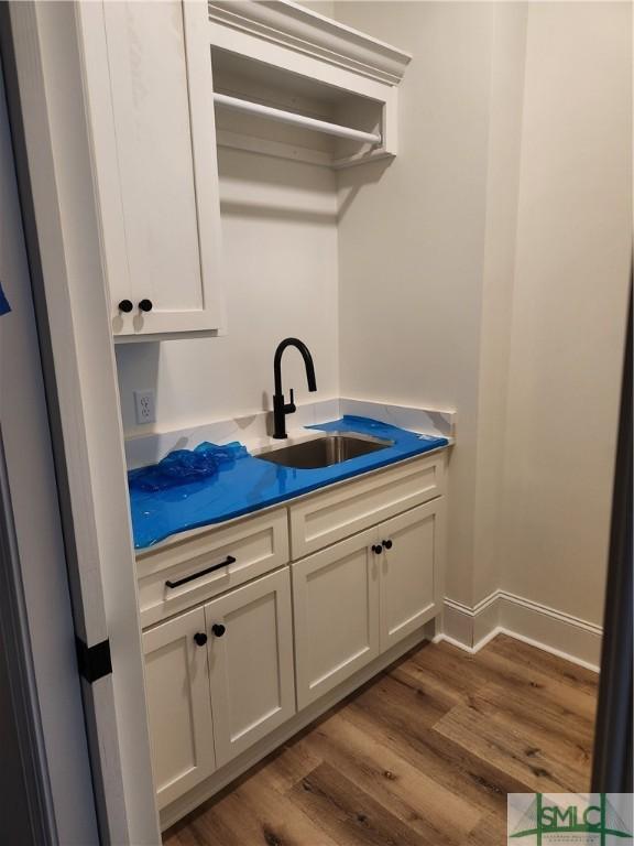 washroom featuring dark wood-type flooring, a sink, and baseboards